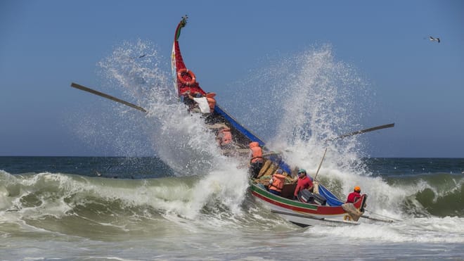 Barco pesquero tradicional cruza olas atlánticas cerca de Aveiro con tripulación