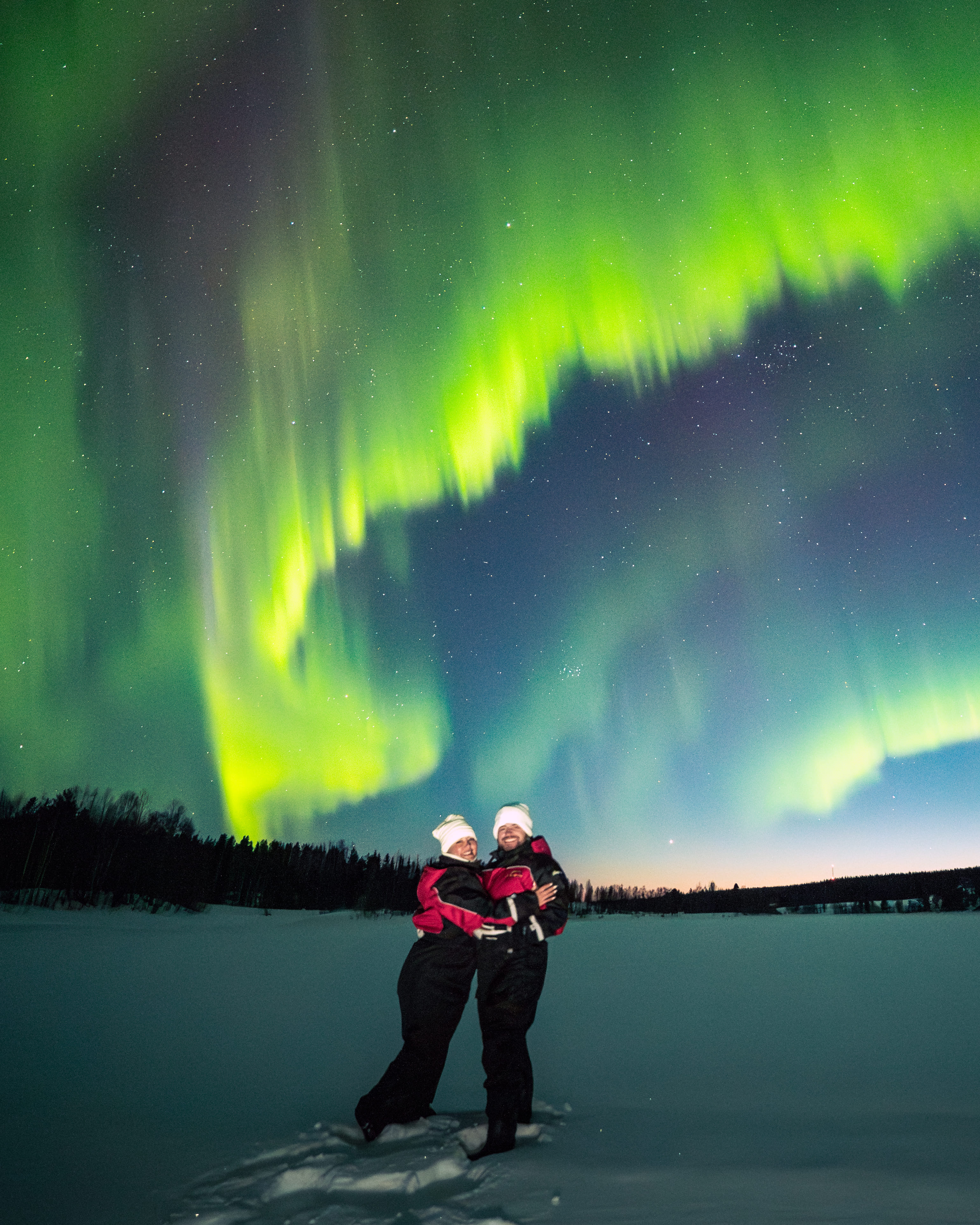 A couple watches the Northern Lights at StayLapland, creating magical moments during a campfire Northern Lights adventure in Rovaniemi.