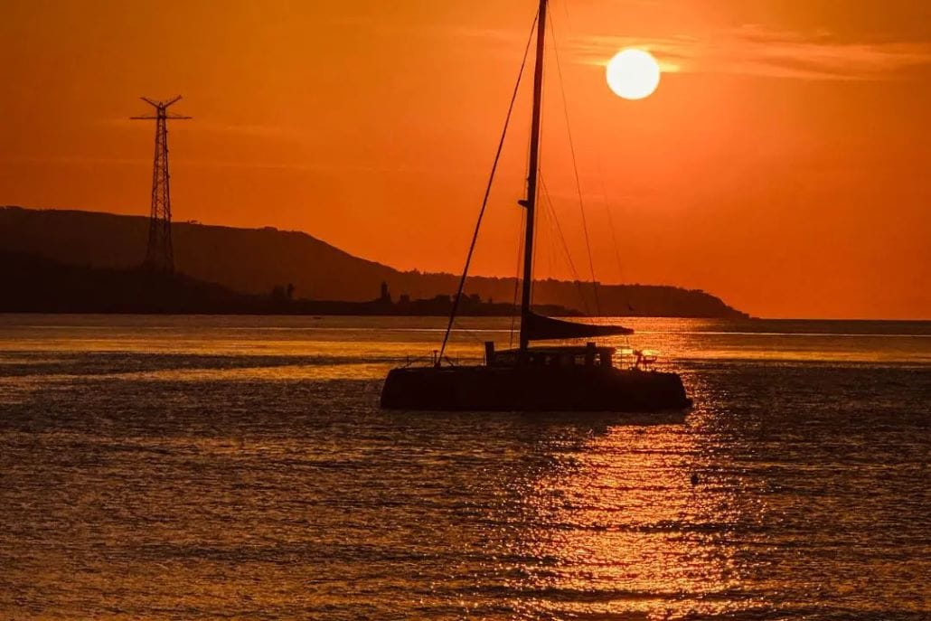 Navigazione in barca al tramonto lungo la Costa Viola
