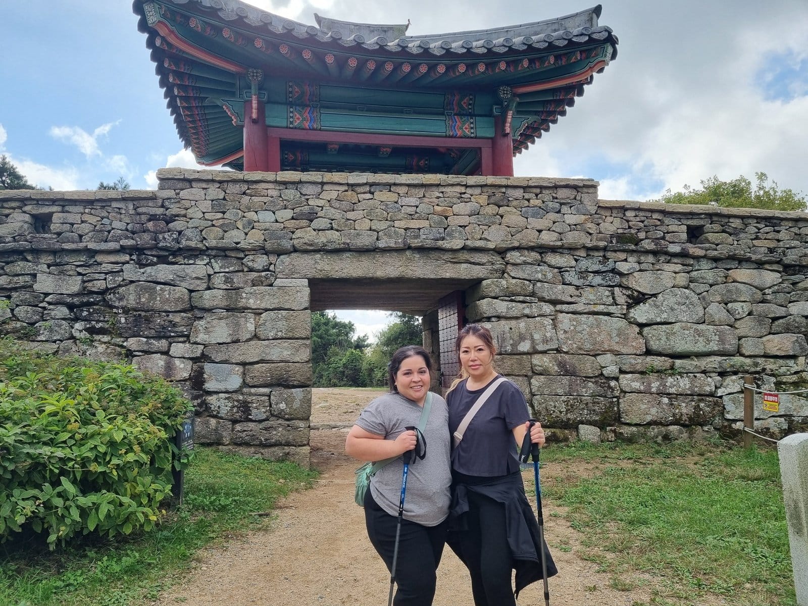 Two women standing in front of the North Gate of Geumjeongsanseong Fortress on Geumjeongsan Mountain.