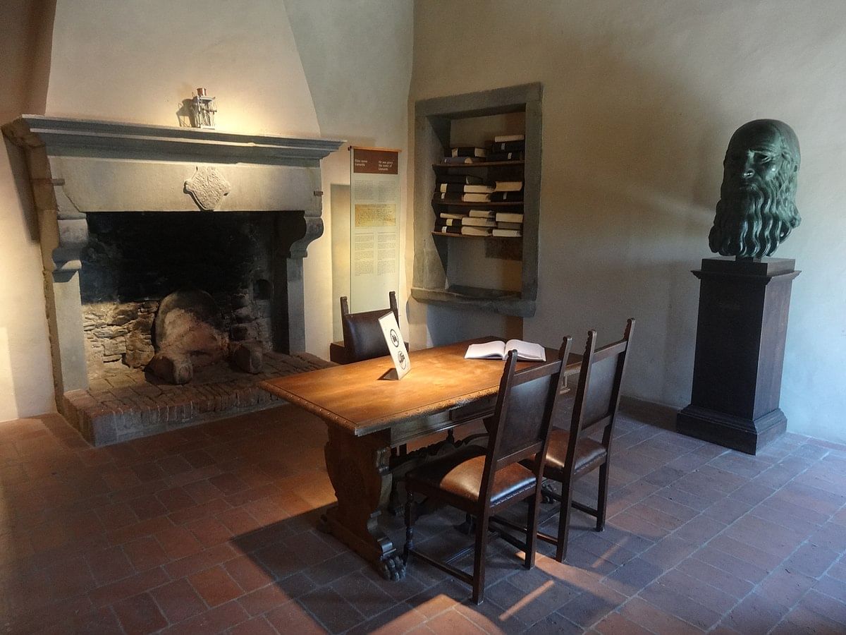 View of one of the rooms inside Leonardo's house in Anchiano, with a fireplce, a table and a bust of Leonardo on the right 
