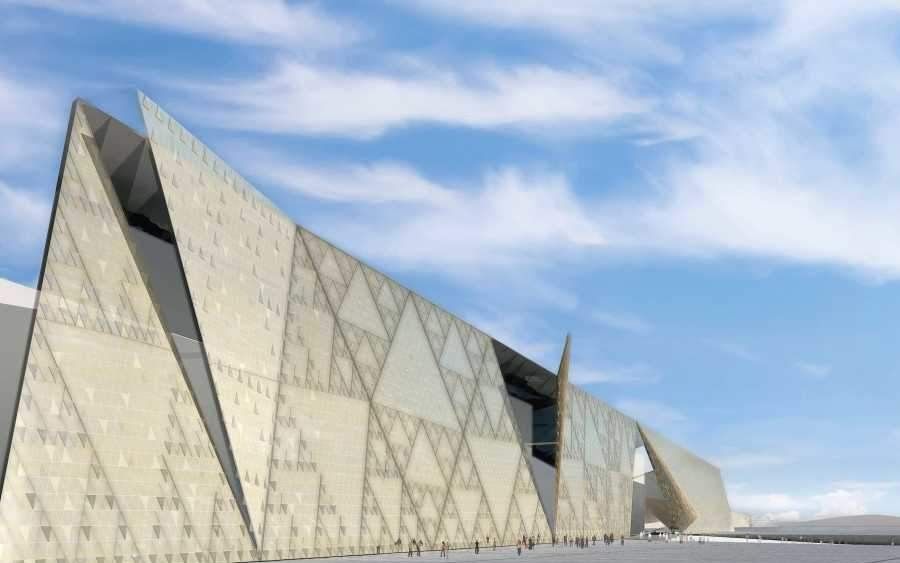 Grand Egyptian Museum exterior with visitors entering the modern glass building near the Giza Plateau.