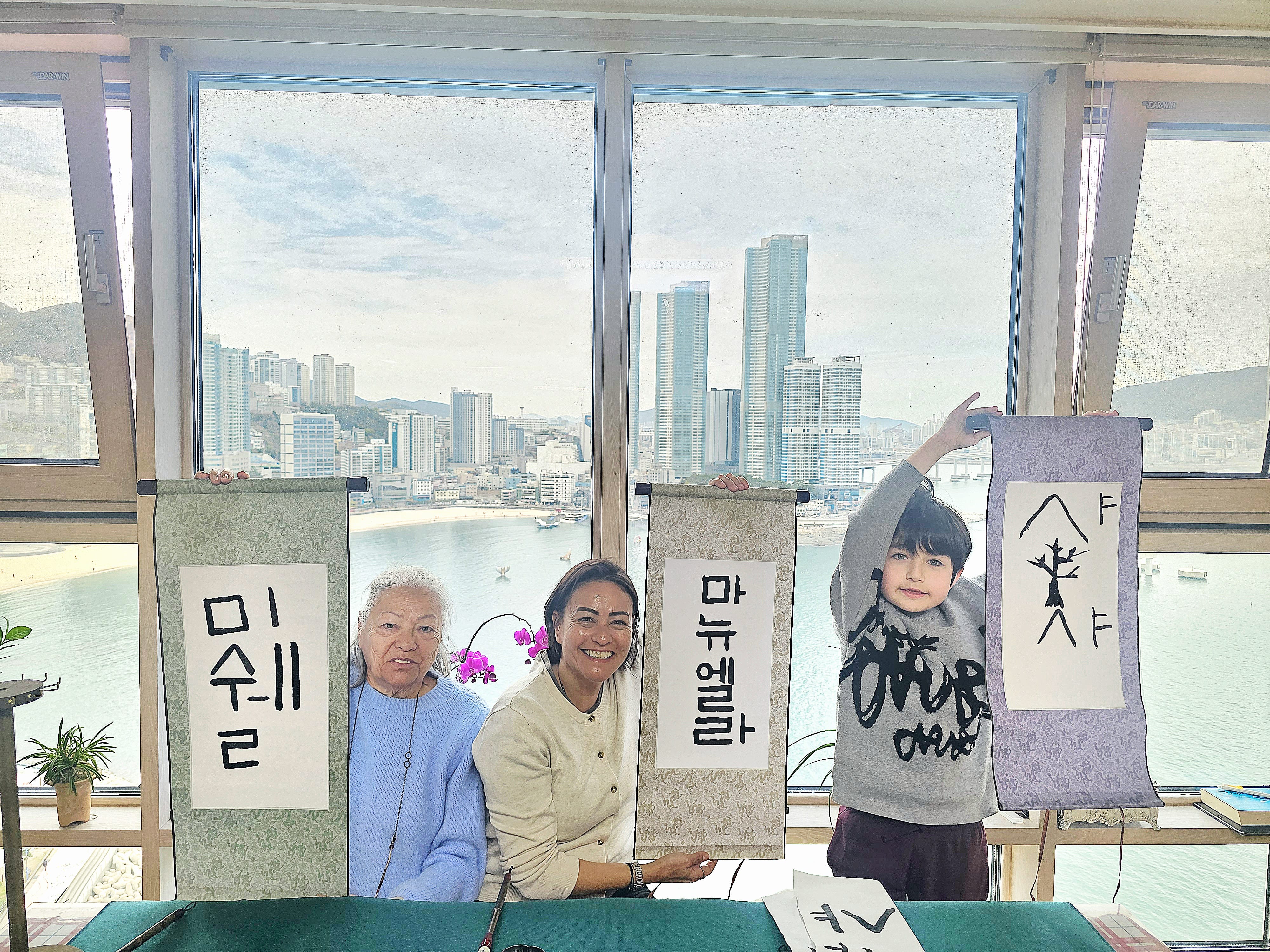 Guests practicing Korean calligraphy inside a local home with a city view in Busan