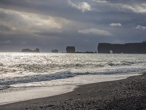 Part of Dyrhólaey seen from Reynisfjara black beach at sunset