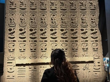 Tourists posing in front of ancient artifacts at the GEM
