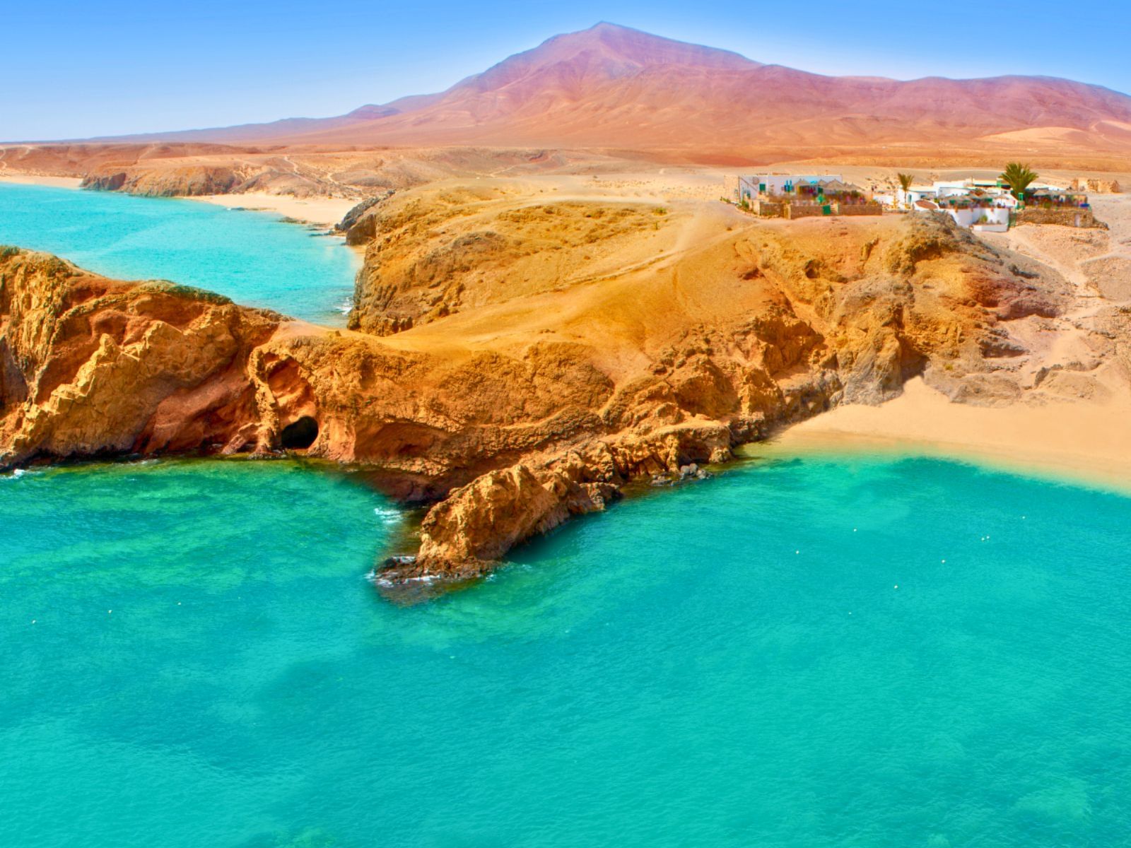 Vista aérea de las Playas de Papagayo destacando las aguas turquesas, arenas doradas y sus paisajes rojizos.