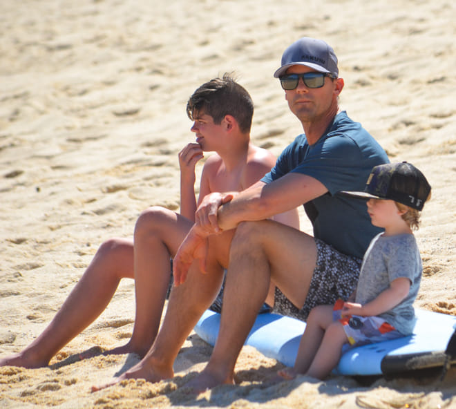 Family sitting on the beach watching surf lessons at Cerritos Beach Los Cabos