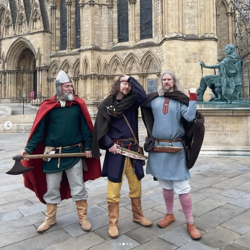 Three viking men stood in front of York Minster, besides the statue of Constantine the Great.