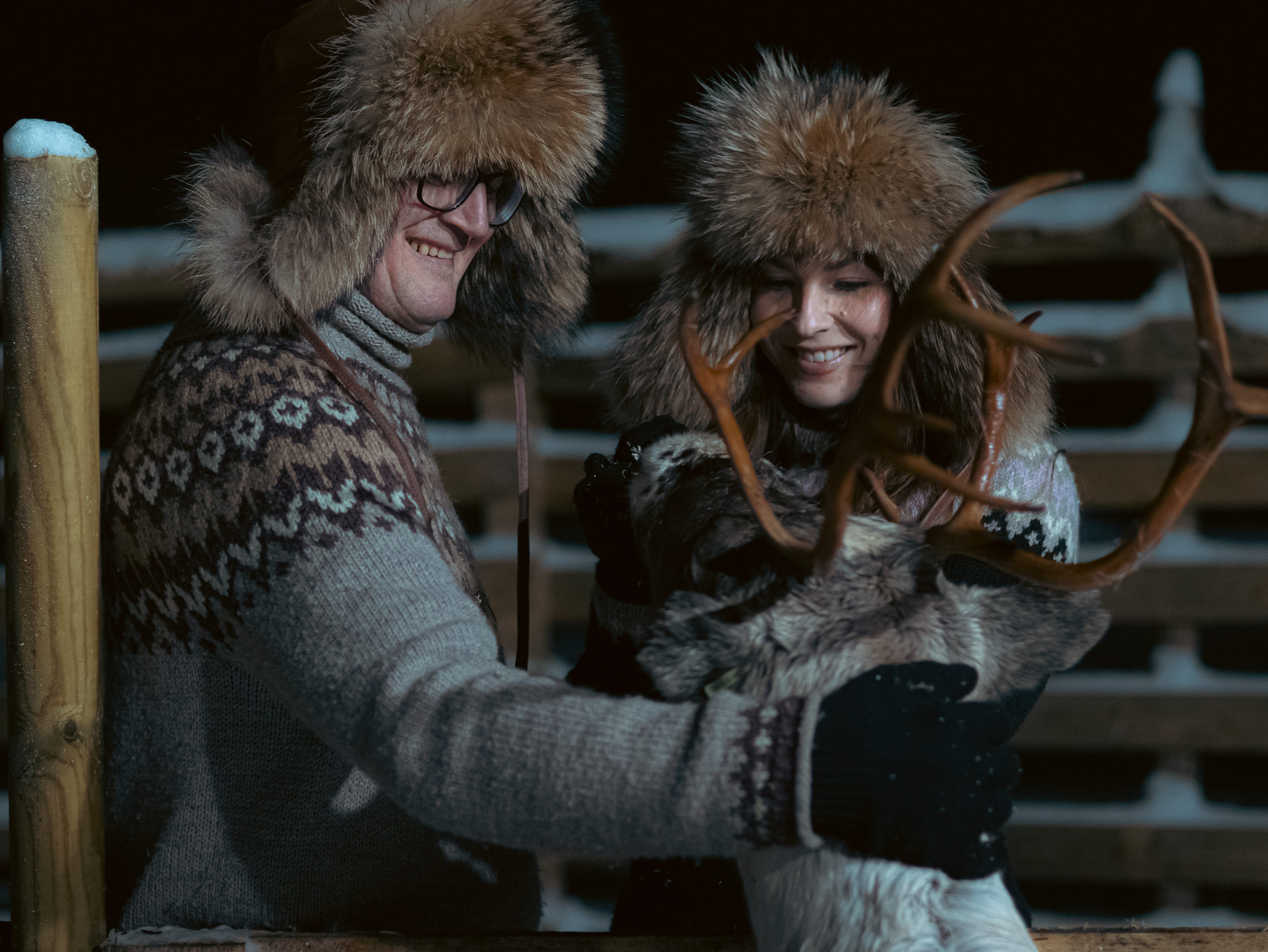 Man and woman feeding a reindeer.