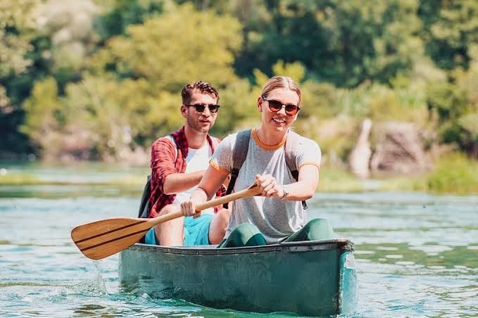 Two tourists paddling a canoe on the calm waters of Momella Lakes in Arusha National Park.