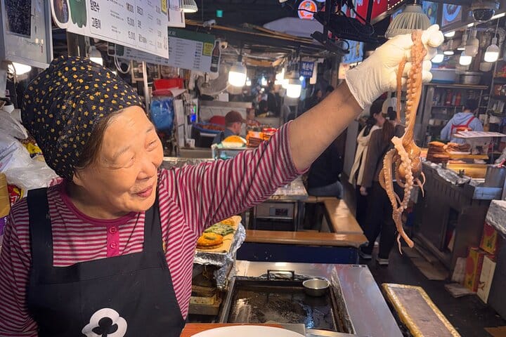 A vendor at Gwangjang Market proudly holding fresh octopus — a lively glimpse into Seoul’s authentic street food culture.A vendor at Gwangjang Market holding a fresh octopus.