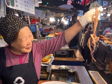A vendor at Gwangjang Market proudly holding fresh octopus — a lively glimpse into Seoul’s authentic street food culture.A vendor at Gwangjang Market holding a fresh octopus.