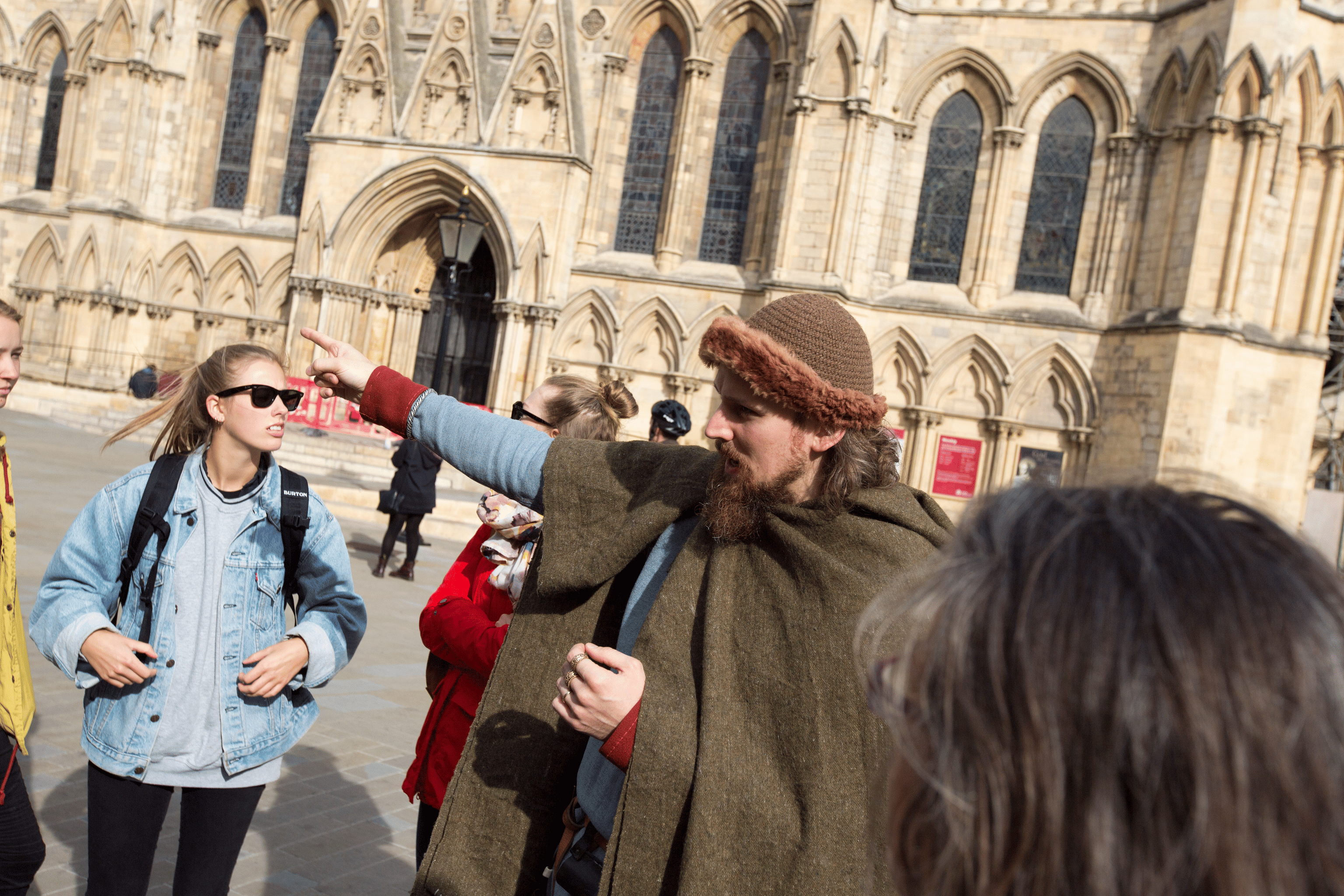 A viking talks to a group of international students with York Minster's amber-coloured stone walls behind him.