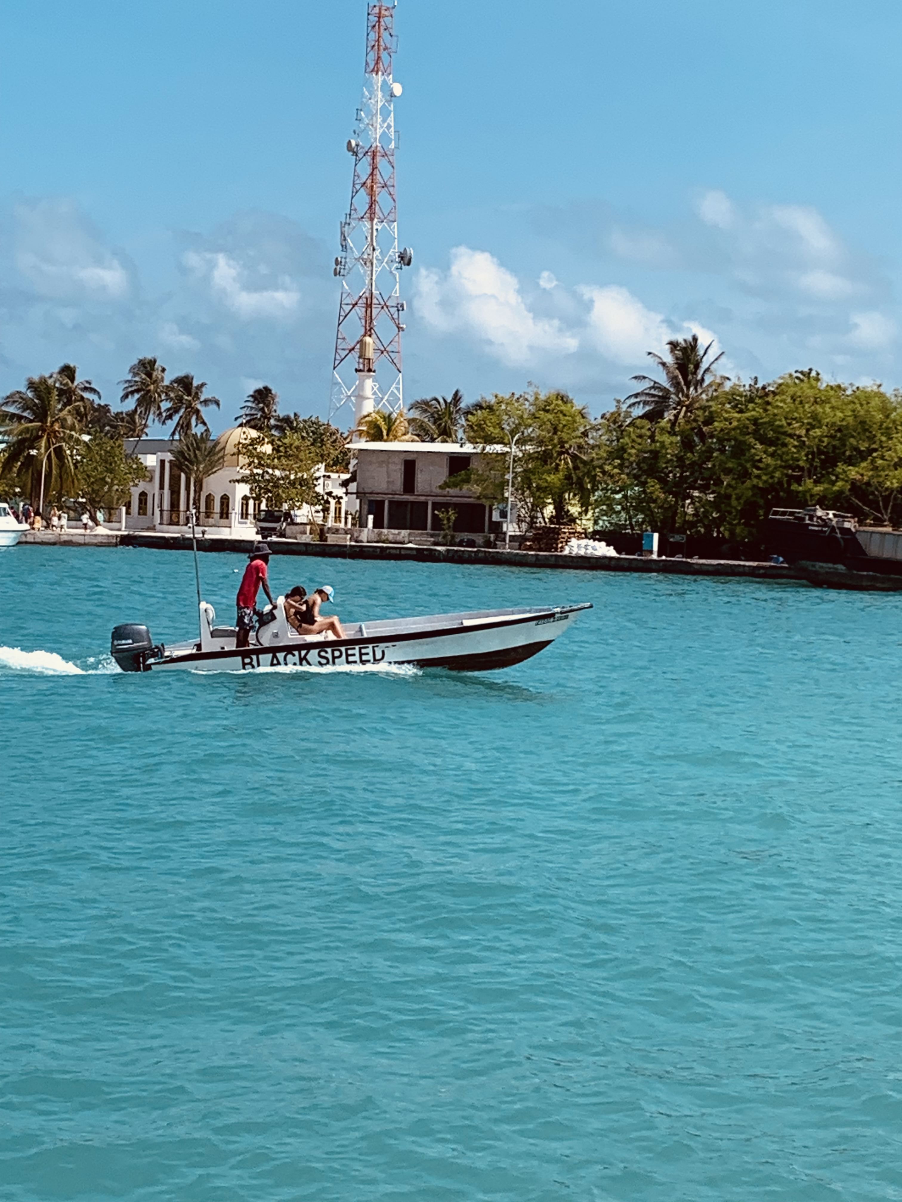 A group enjoying a dinghy ride from Jailbreak surfing point back to Himmafushi, surrounded by crystal-clear waters and a vibrant sky