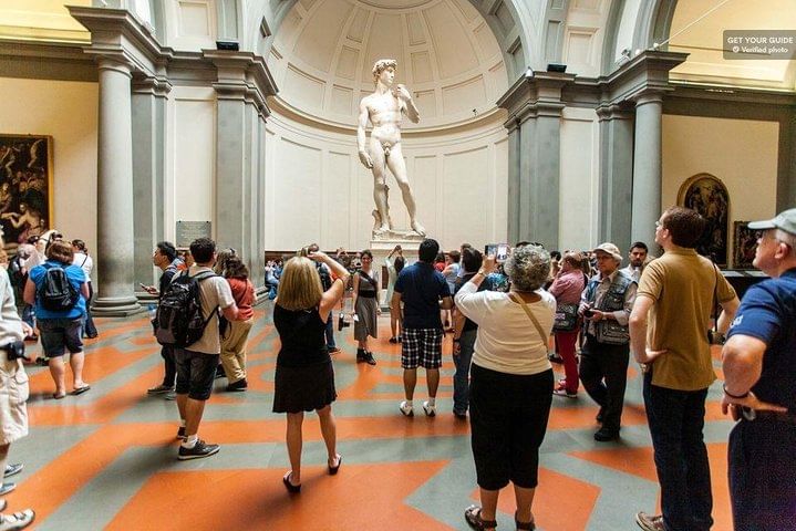 View of Michelangelo's David with a crowd of people admiring it all around 