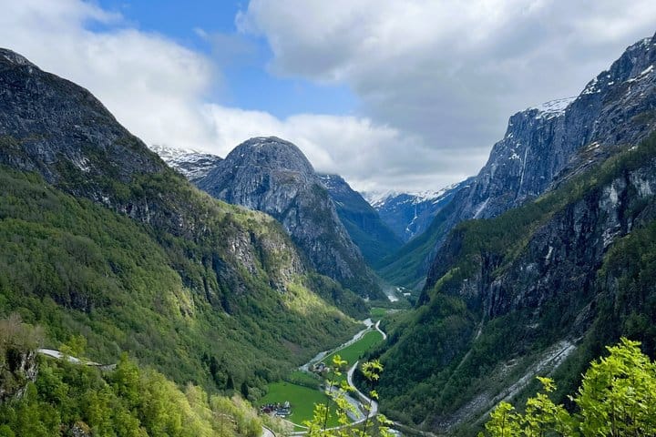 Green Flåm Valley framed by steep mountains and snowy peaks