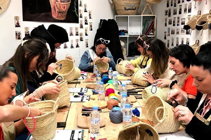 Group of participants focused on embroidering and personalizing palm-leaf baskets during a creative workshop in Marrakech.