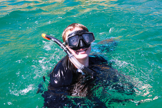 Young snorkeler smiling in turquoise ocean water during a snorkeling tour in Los Cabos
