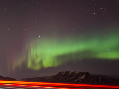 Aurora seen from a parking lot with beam light of a passing car