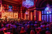 Orchestra on stage at live classical concert Vienna with red and blue atmospheric lighting