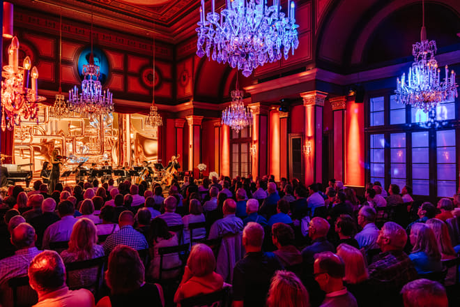Orchestra on stage at live classical concert Vienna with red and blue atmospheric lighting