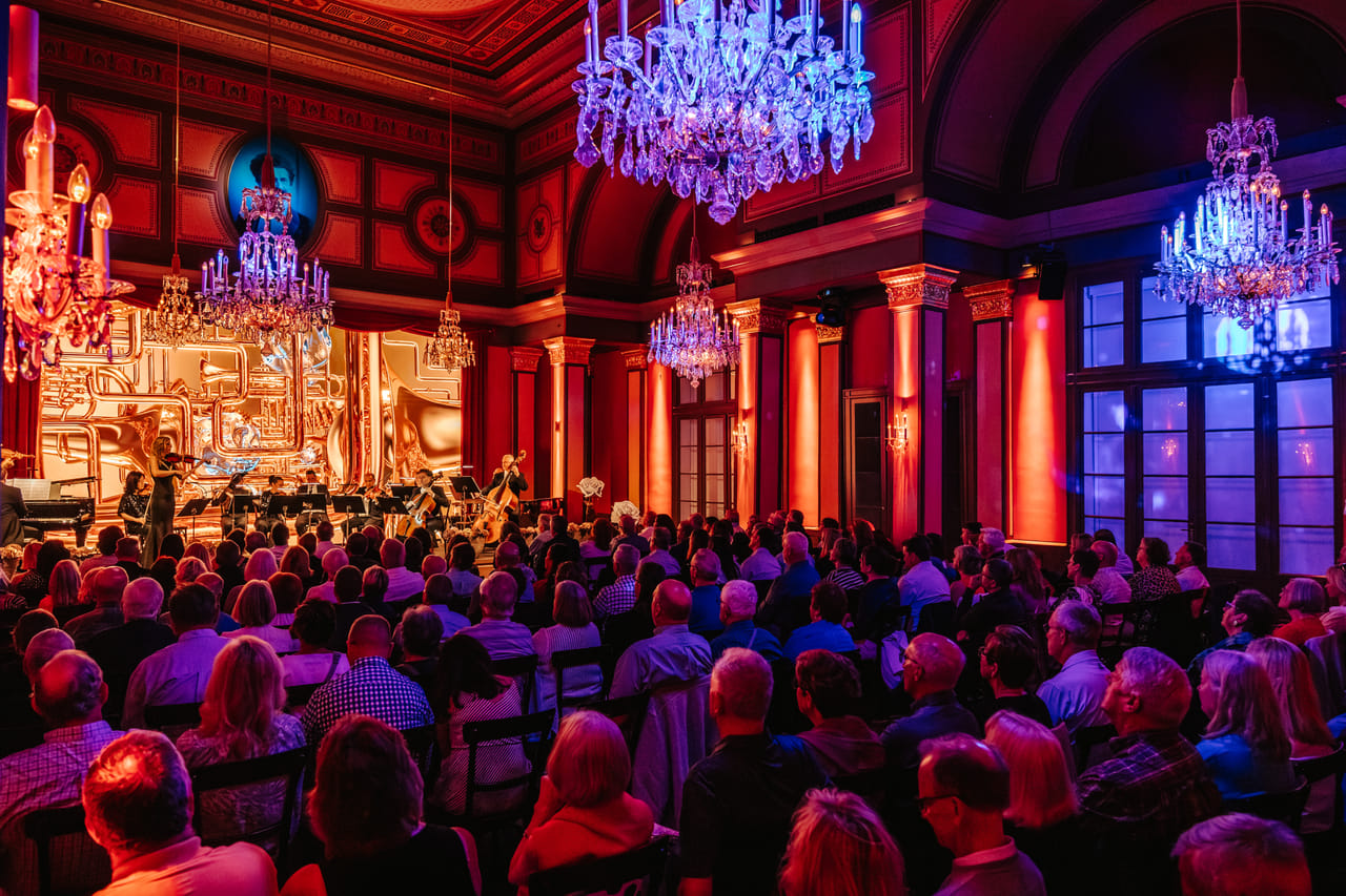 Orchestra on stage at live classical concert Vienna with red and blue atmospheric lighting