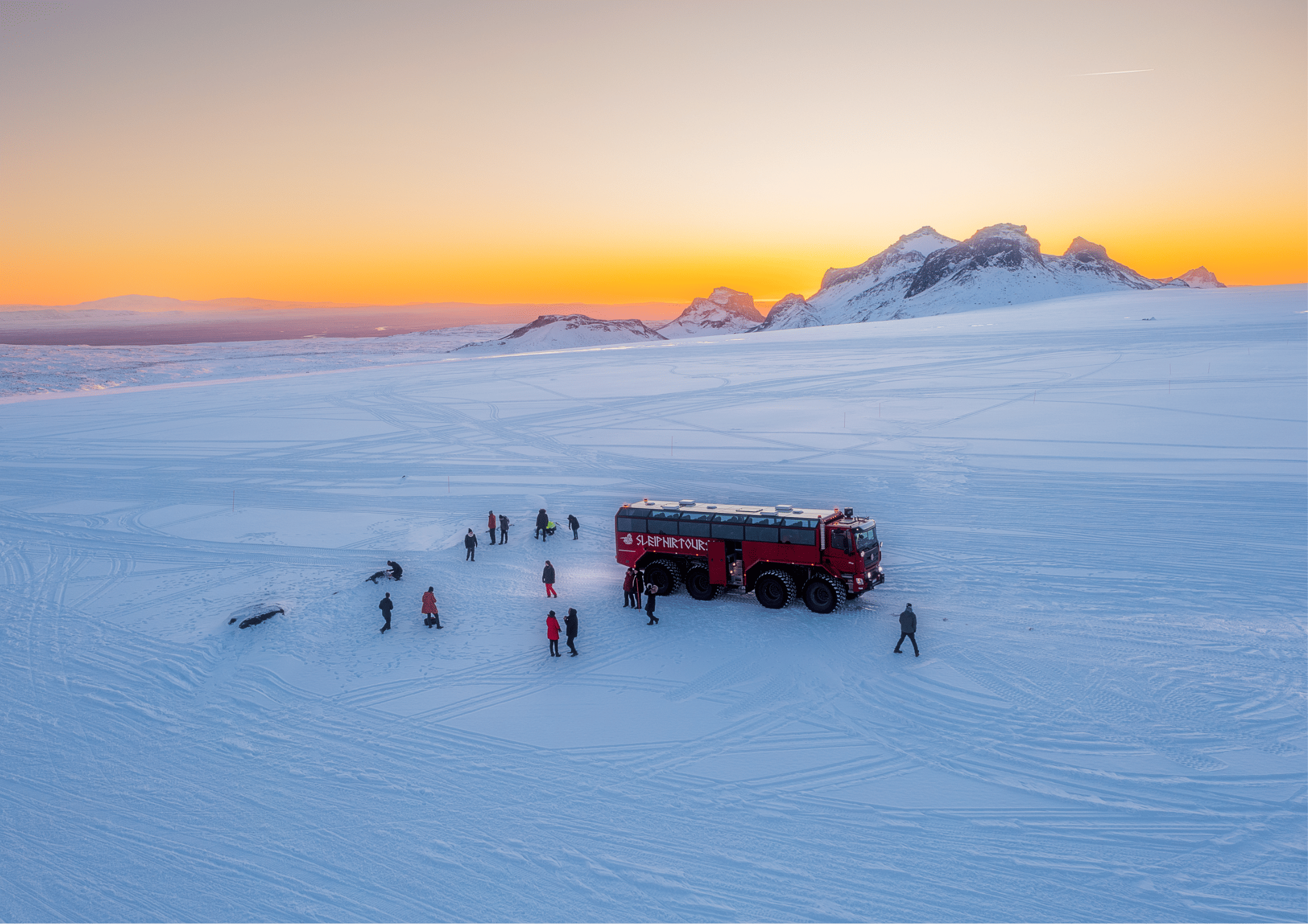 Monster Truck on glacier, with guests walkin on the snow and ice. 