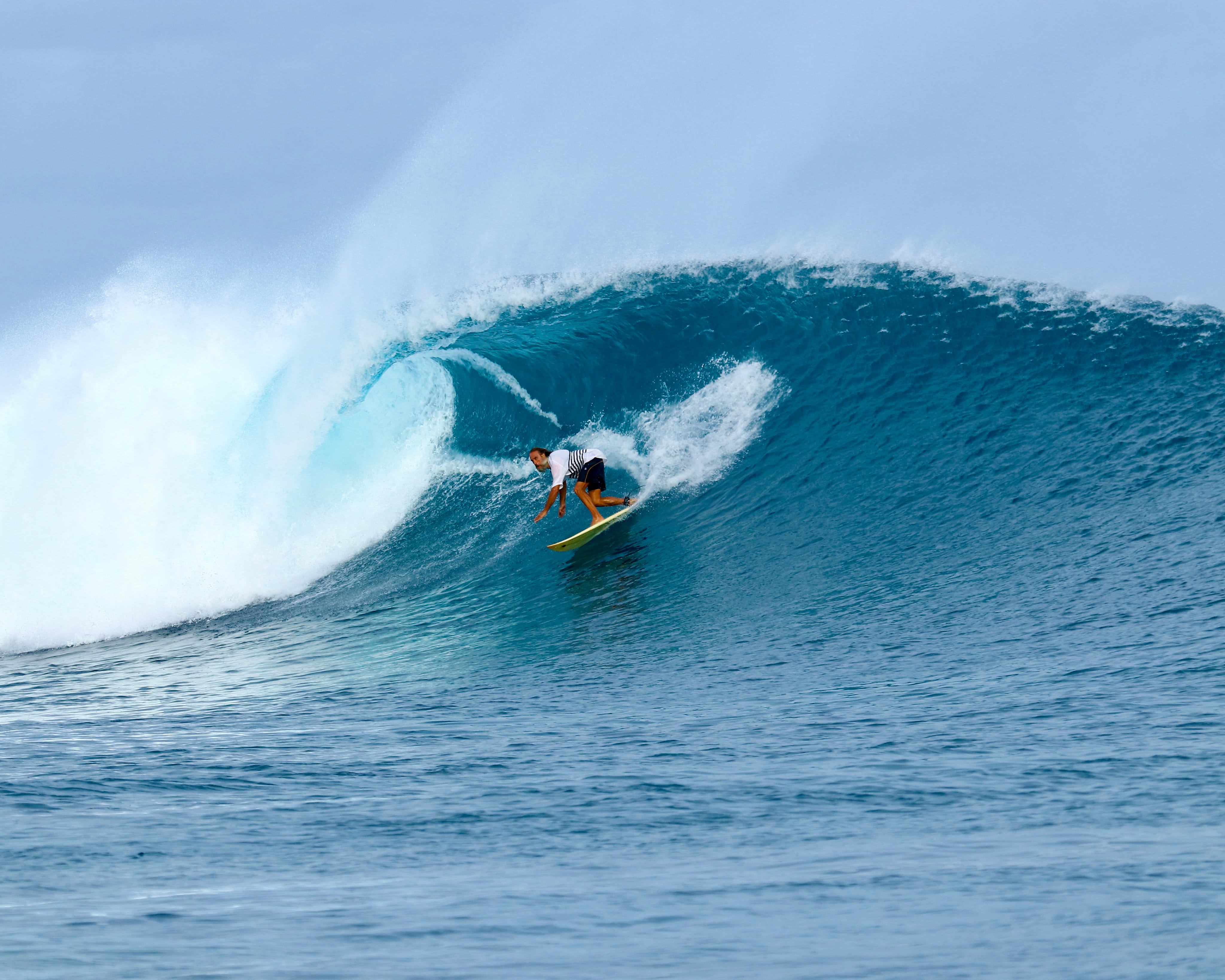 Foto de acción de un surfista surfeando entre las olas en Honkeys, en la isla de Himmafushi, reservada a través de ForBeyond Travel