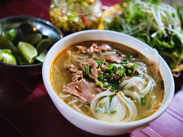 Bun Bo Hue – A symbolic dish of Hue, with rich, flavorful broth, rice noodles, beef balls, pig's trotters, blood pudding, and fresh herbs.