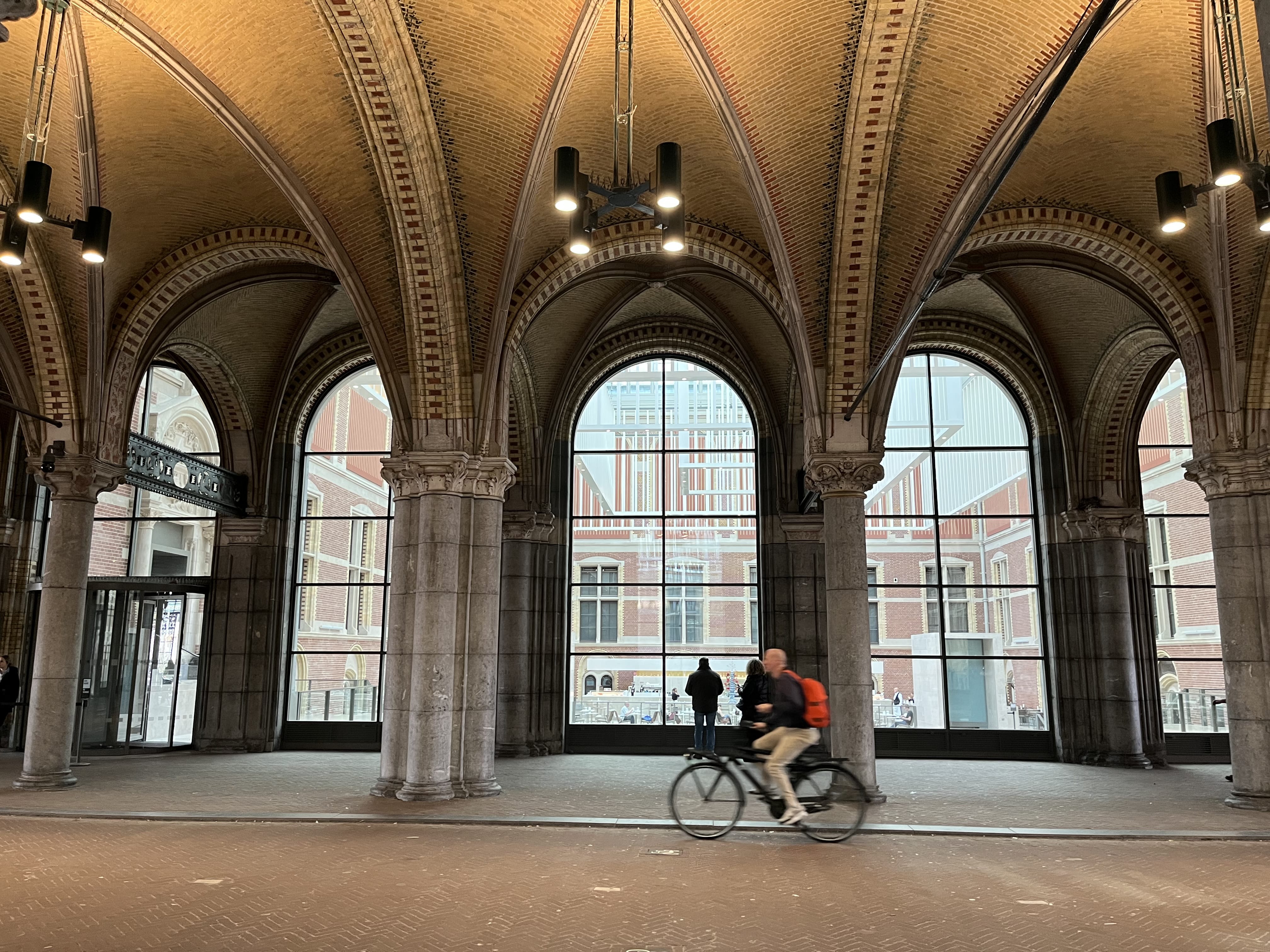 Cyclist passing through historic archway in Amsterdam during a private hop-on hop-off city tour