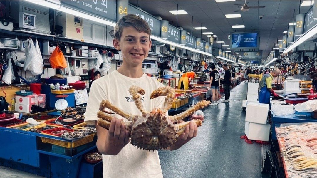A tourist holding a live king crab inside Jagalchi Market’s seafood area.