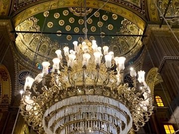 Ornate central chandelier illuminating the grand Ottoman-style interior dome of the Mosque of Muhammad Ali in Cairo, Egypt.
