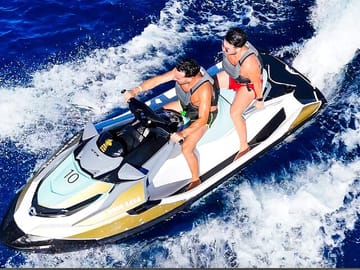 Two friends speeding across the blue waters on a jet ski near Blue Lagoon during the adventurous 45-minute Malta Jet Ski Safari.