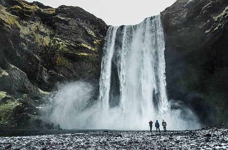 Skogafoss waterfall with people standing next to falls