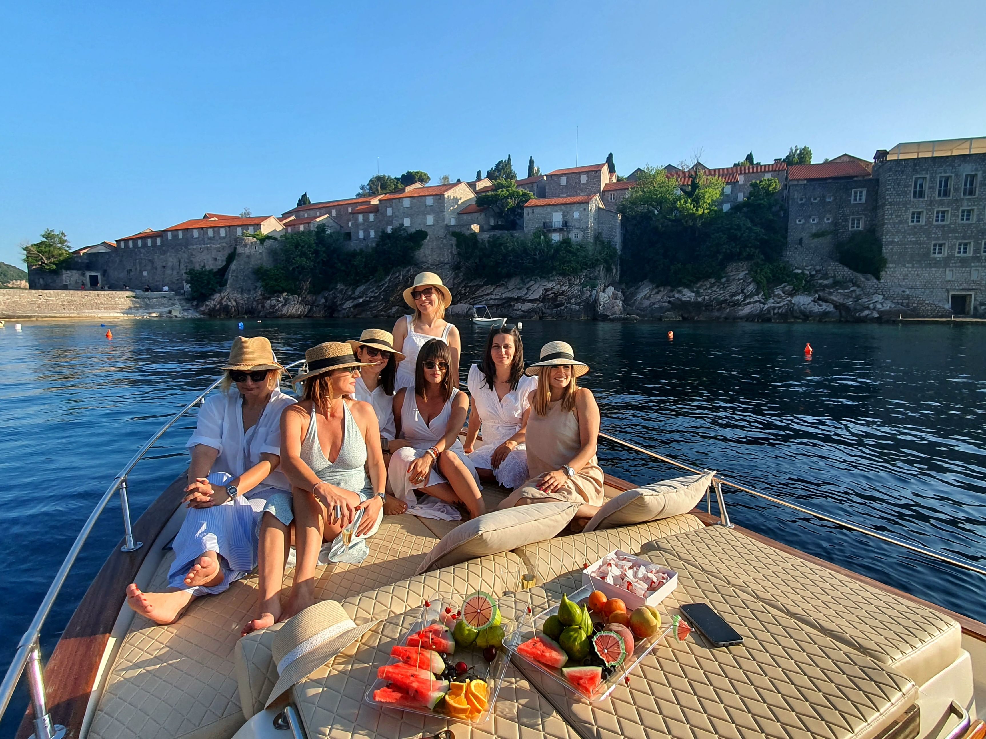 A group of friends sharing laughs as they dip their feet into the crystal-clear water from the boat.
