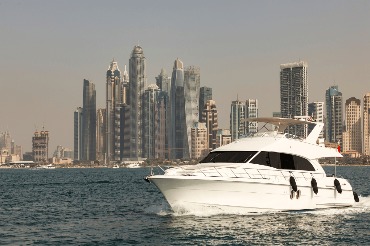 White yacht cruising along Dubai’s coastline with city skyline in the background