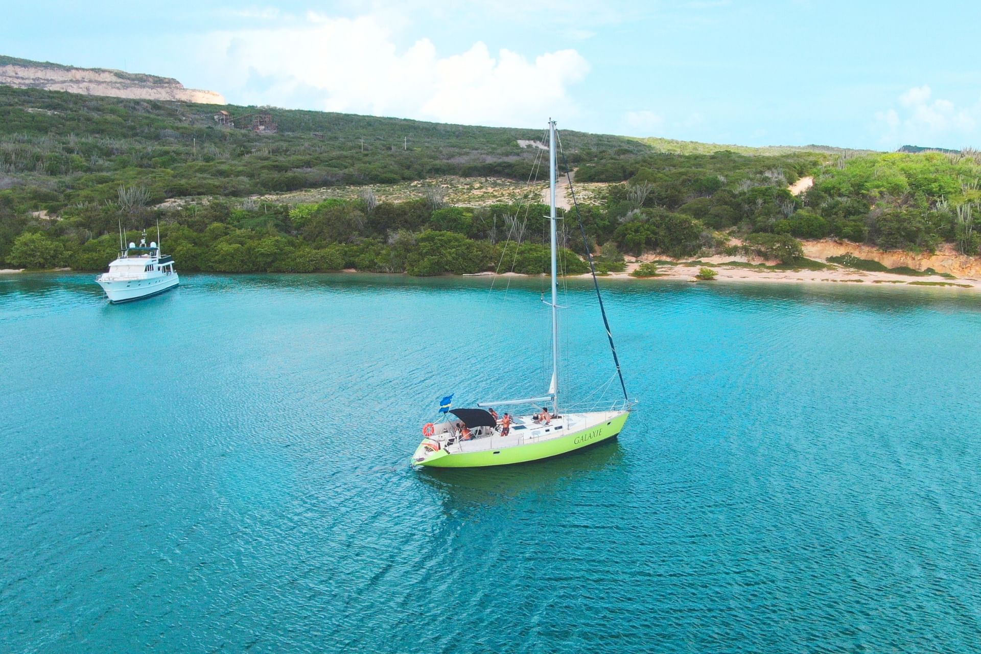 Green sailing yacht Galaxie anchored at serene blue waters of Fuik Bay in Curacao