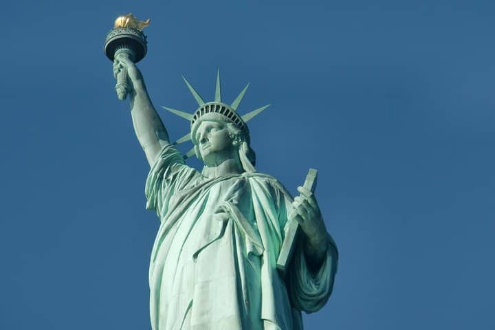 Statue of Liberty holding torch against clear blue sky