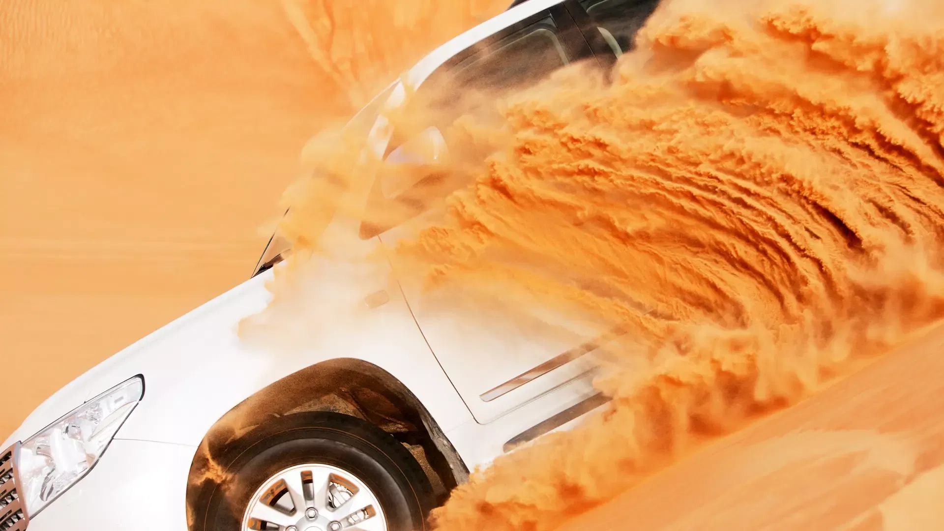 A white off-road vehicle kicks up a massive cloud of sand while driving through the dunes at Desert Safari + Al Faqaa Camp.