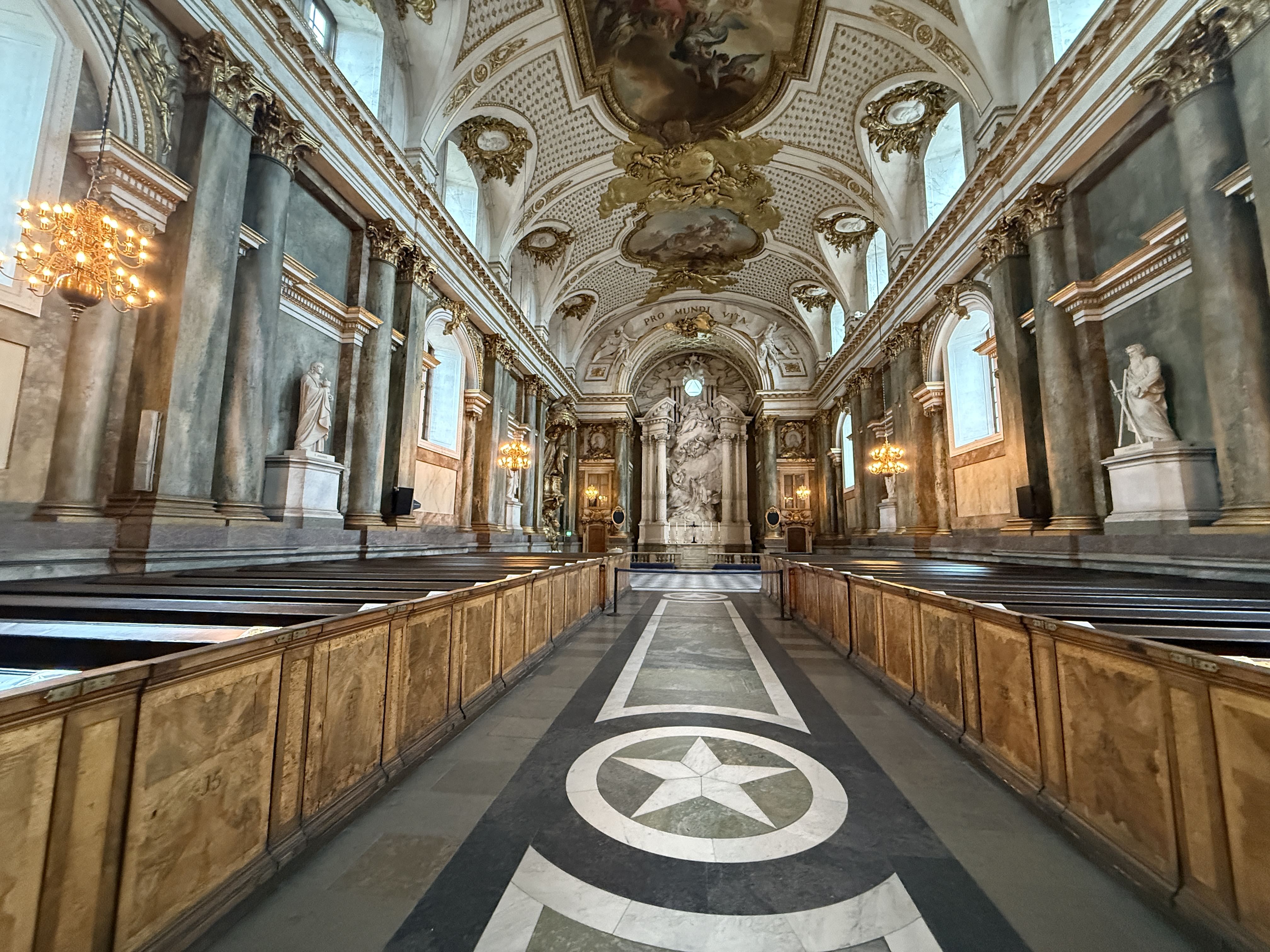 Ornate interior of the Royal Chapel with marble columns, gold accents, statues, and a central altar beneath a painted vaulted ceiling.