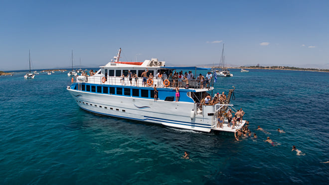 Passengers aboard a blue-and-white cruise boat with swimmers alongside