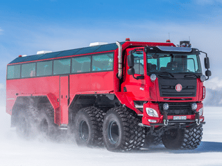 Red Monster truck driving on snow on the glacier