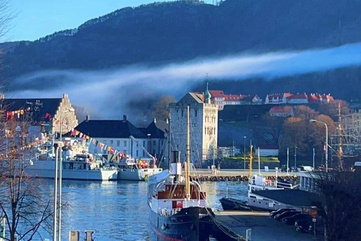 Misty Bergen harbor with boats and Bergenhus Fortress