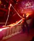 An overhead view of an audience seated around a lava channel in a dark theater, watching the glowing lava flow through the stage.