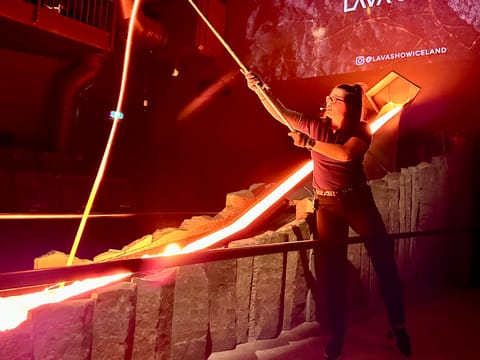 An overhead view of an audience seated around a lava channel in a dark theater, watching the glowing lava flow through the stage.
