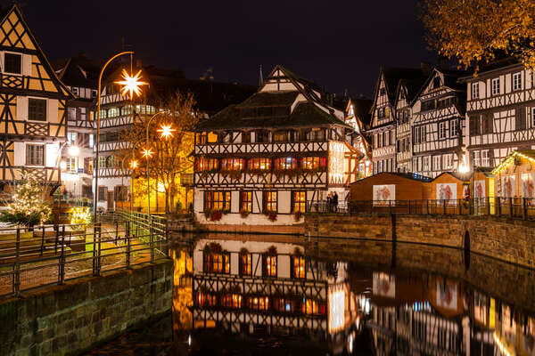 A Petite France à noite, com as casas enxaimel refletidas no canal.