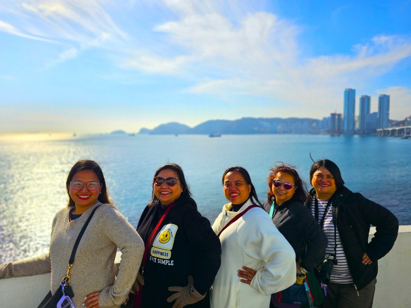 Tourists standing on the seaside walkway with colorful buildings in Huinnyeoul Culture Village.
