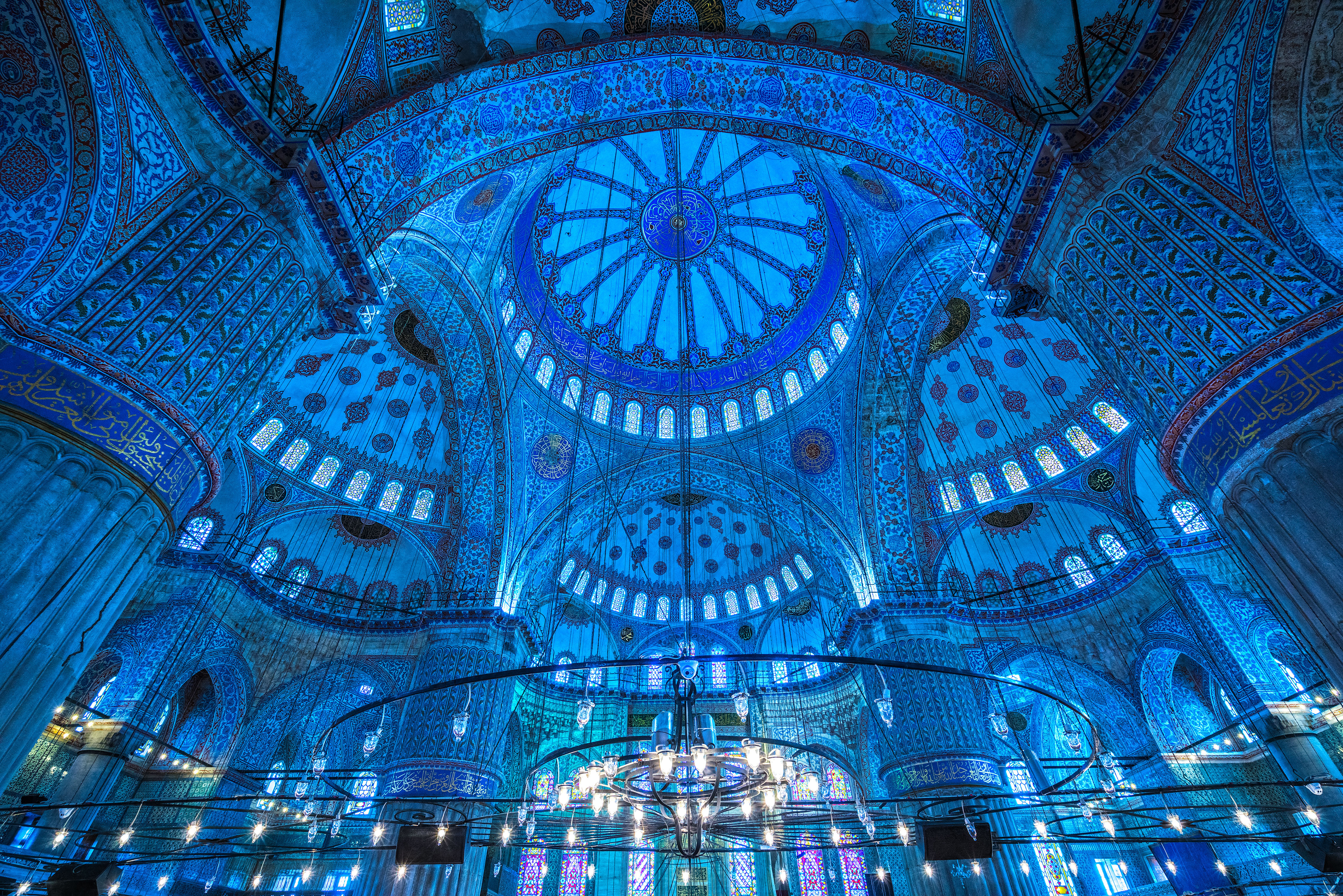 “Interior view of the Blue Mosque dome, showing detailed Iznik tile patterns and  calligraphy decorating the circular ceiling.”