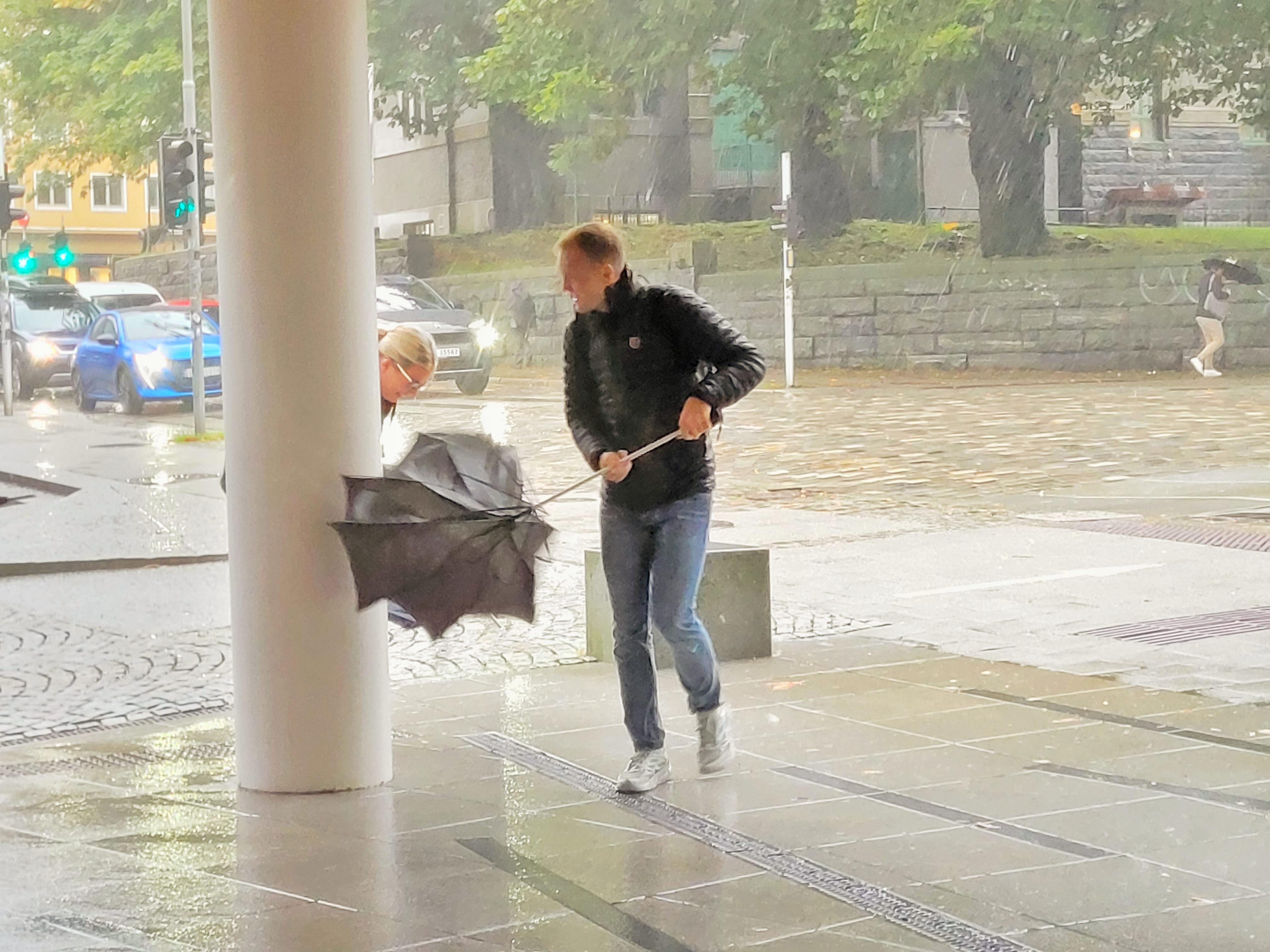 Person walking through rain with an umbrella, showing atmospheric street moments explored during the photowalk.