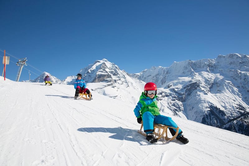 Descida de trenó em Mürren, com os Alpes nevados ao fundo.